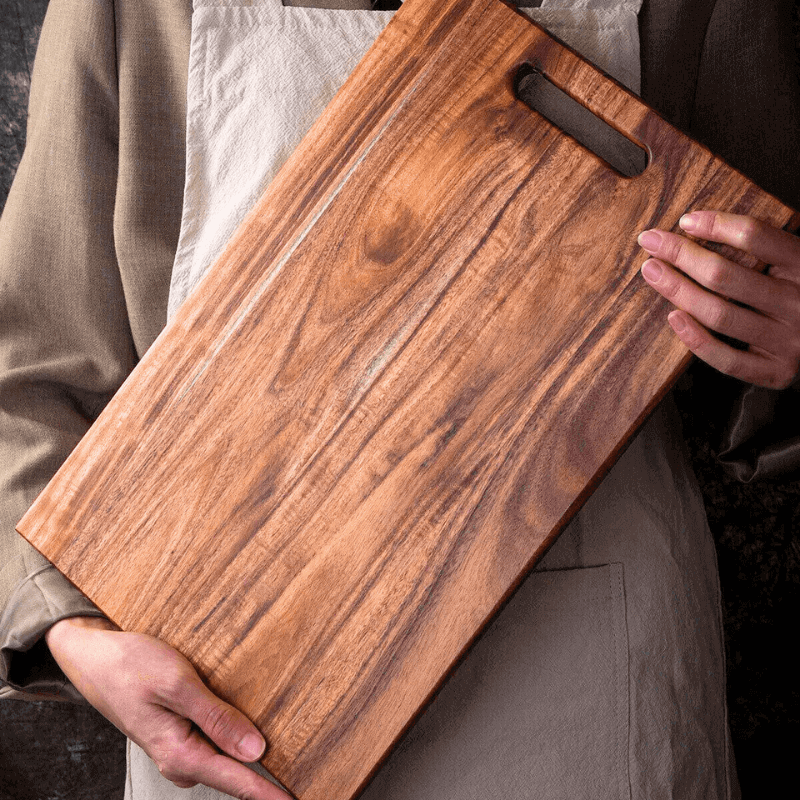 Person holding a wooden cutting board with a handle
