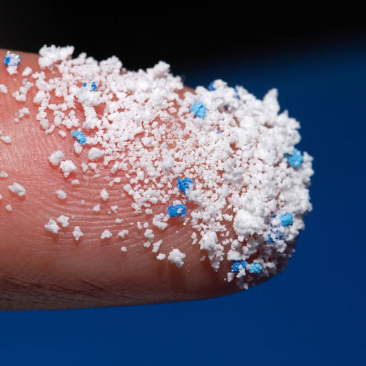 Close-up shot of microplastic particles on a fingertip.