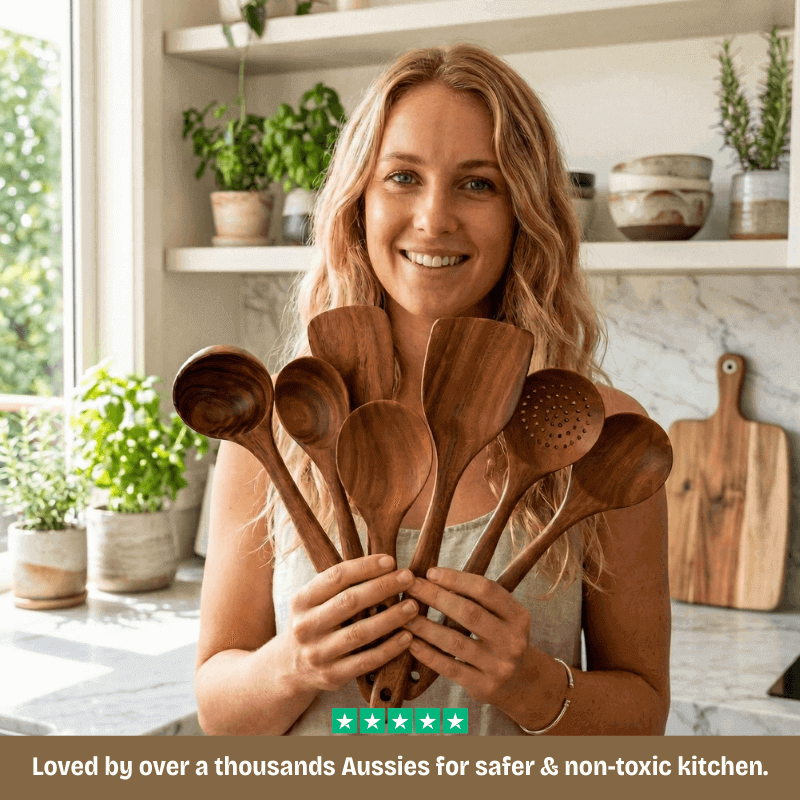 Woman holding wooden spoons in a kitchen with plants and shelves in the background