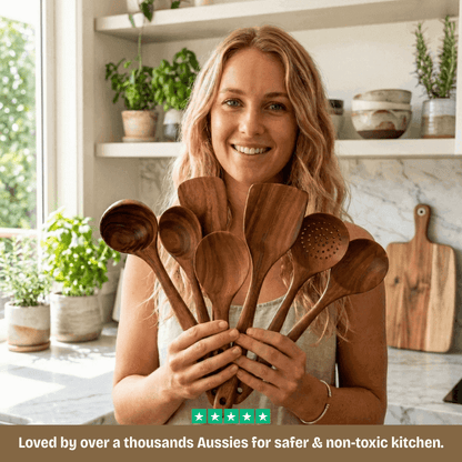 Woman holding wooden spoons in a kitchen with plants and shelves in the background