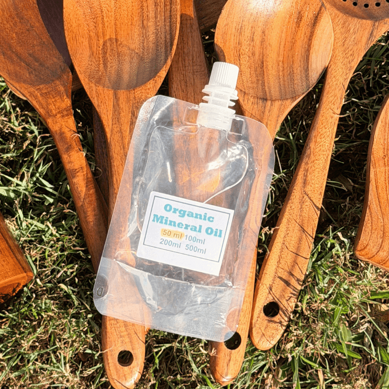 Wooden spoons with a bottle of organic mineral oil on grass