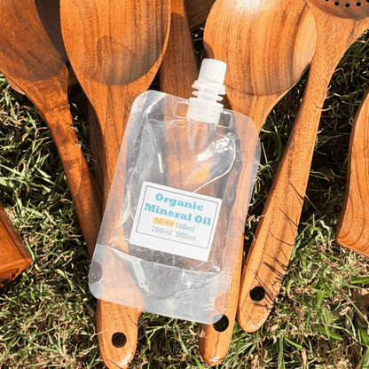 Wooden spoons with a bottle of organic mineral oil on grass