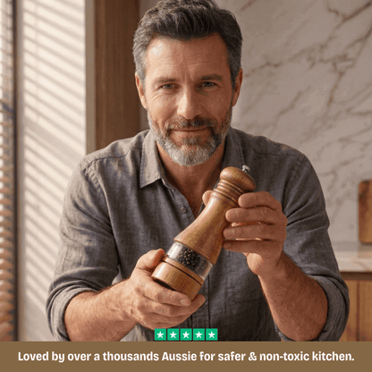 Man holding a wooden pepper grinder in a kitchen setting