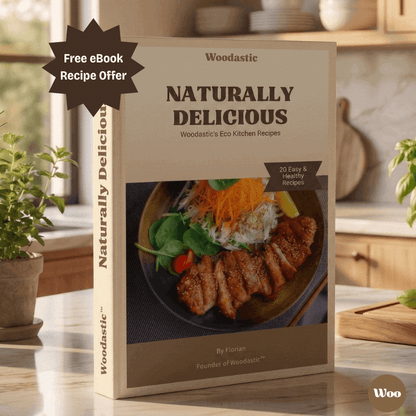 Woodastic 'Naturally Delicious' recipe book on a kitchen counter with plants and a cutting board.