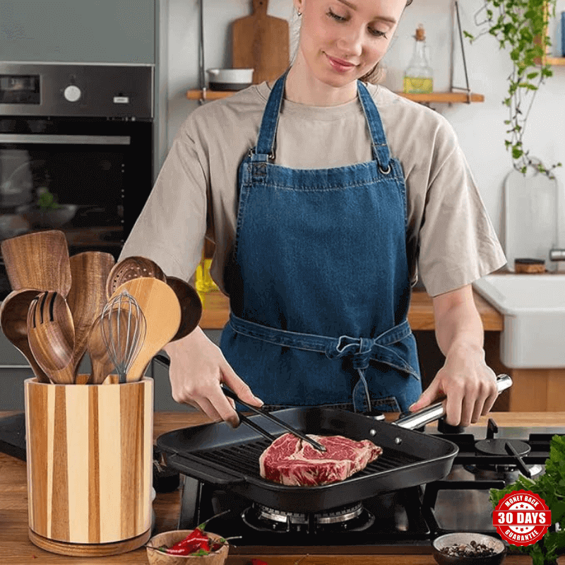 Women cooking steak inside her kitchen, with wooden holder and utensils display in front