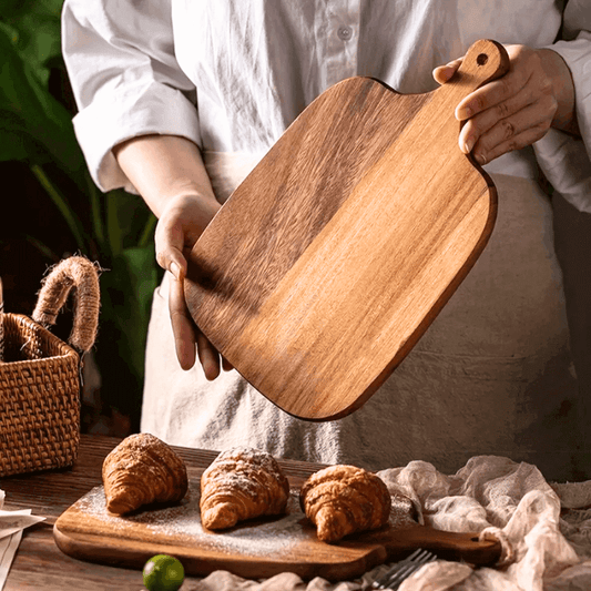 Person holding a wooden cutting board with pastries on a rustic setting