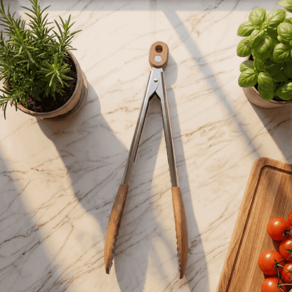 Wooden-handled tongs on a marble surface with potted herbs and tomatoes.