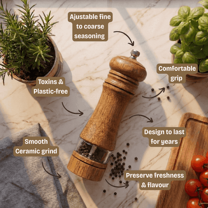 Wooden pepper grinder with text highlighting features on a marble surface with herbs and tomatoes.